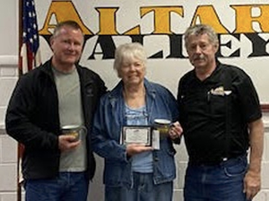 Patzi holding award next to two men